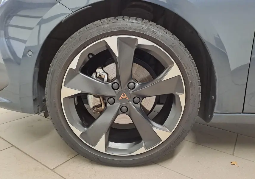 Gros plan sur la roue avant gauche d'une CUPRA Leon gris magnétique 2023 avec jante alliage bicolore et logo CUPRA central.
