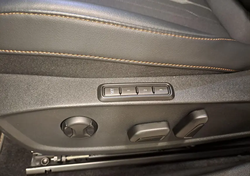 Détail des commandes de réglage électrique du siège conducteur avec surpiqûres orange sur cuir noir dans une CUPRA Leon 2023.