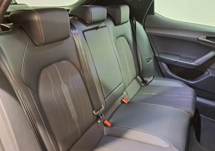 Vue intérieure du siège arrière droit en cuir noir avec surpiqûres orange de la CUPRA Leon 1.5 eTSI 2023 gris magnétique.