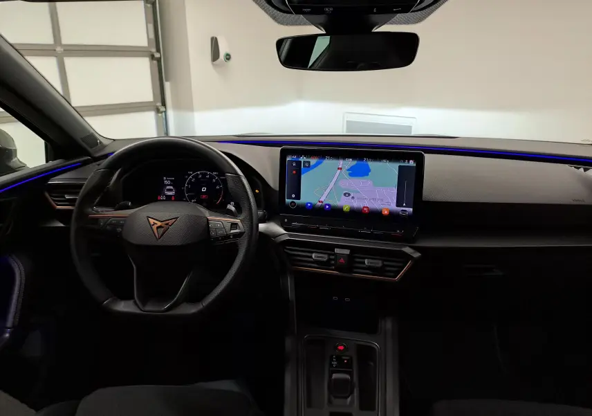 Vue intérieure avant du CUPRA Leon 1.5 eTSI 2023 avec tableau de bord numérique et écran tactile de navigation.
