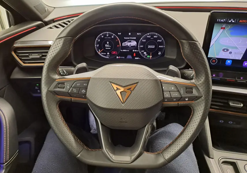 Vue rapprochée du volant perforé avec logo CUPRA cuivré et tableau de bord numérique du Leon 1.5 eTSI gris magnétique 2023.