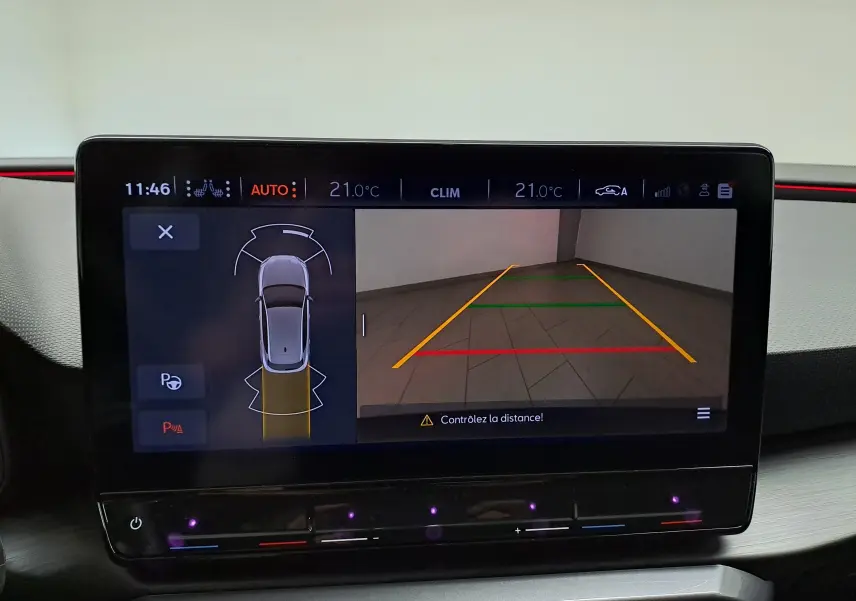 Écran tactile intérieur montrant la caméra de recul et l'assistance au stationnement du CUPRA Leon gris magnétique 2023.