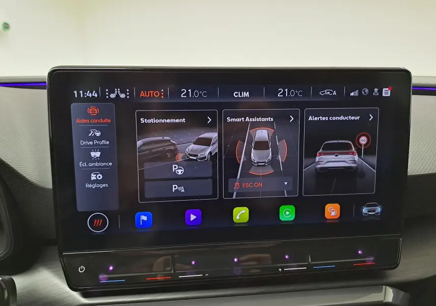 Écran tactile central du tableau de bord du CUPRA Leon 2023 montrant les aides à la conduite et la climatisation.
