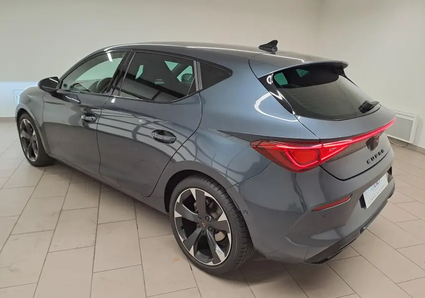 Vue 3/4 arrière droite d'une CUPRA Leon 2023 gris magnétique avec feux arrière LED et jantes noires distinctives.