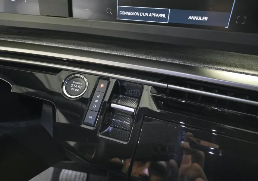Gros plan sur la console centrale noire laquée du Peugeot 3008 gris 2025, avec bouton start/stop et sélecteur de boîte auto.