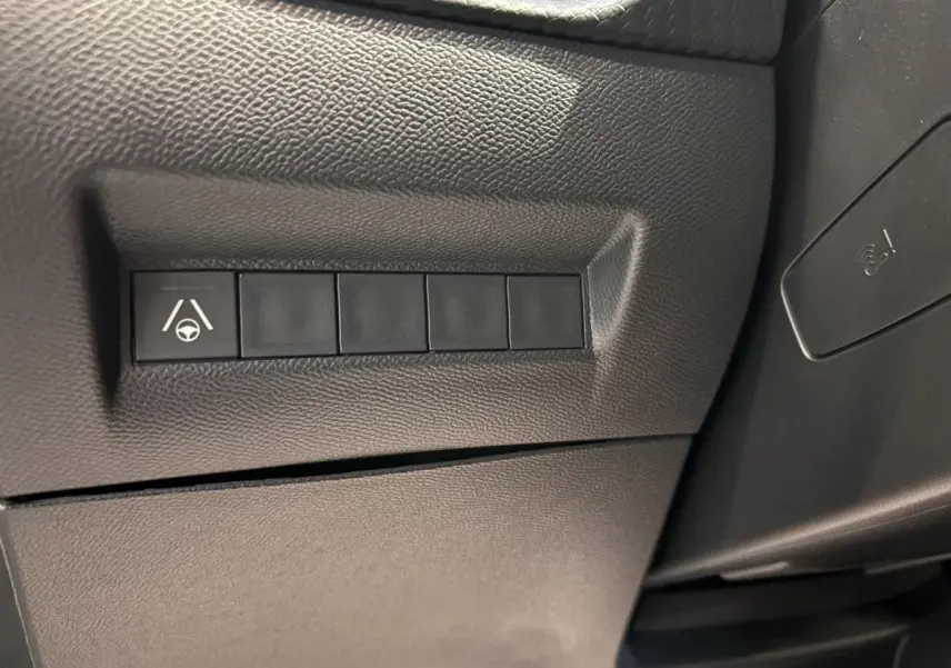 Gros plan sur le tableau de bord noir du Peugeot 2008 1.2i Hybrid GT avec bouton d’aide au maintien de voie.