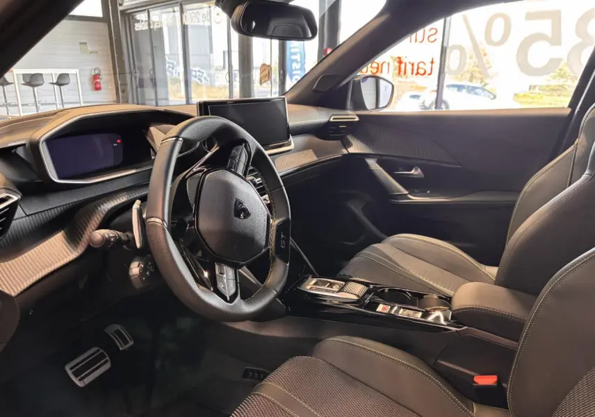 Vue intérieure côté conducteur du Peugeot 2008 1.2i Hybrid GT 2025, volant compact cuir et planche de bord moderne noire.