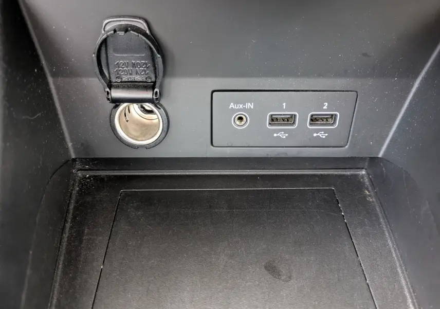 Vue rapprochée de la prise 12V, port Aux-IN et deux ports USB noirs dans la console centrale du Renault Captur Business DCI 95.