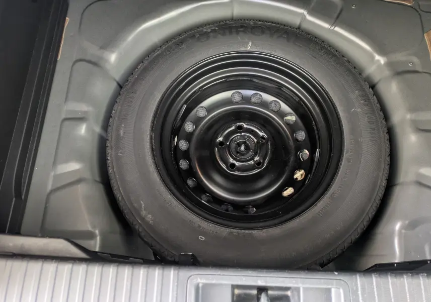 Vue plongeante sur la roue de secours noire logée dans le coffre du Renault Captur Business DCI 95 noir de 2020.