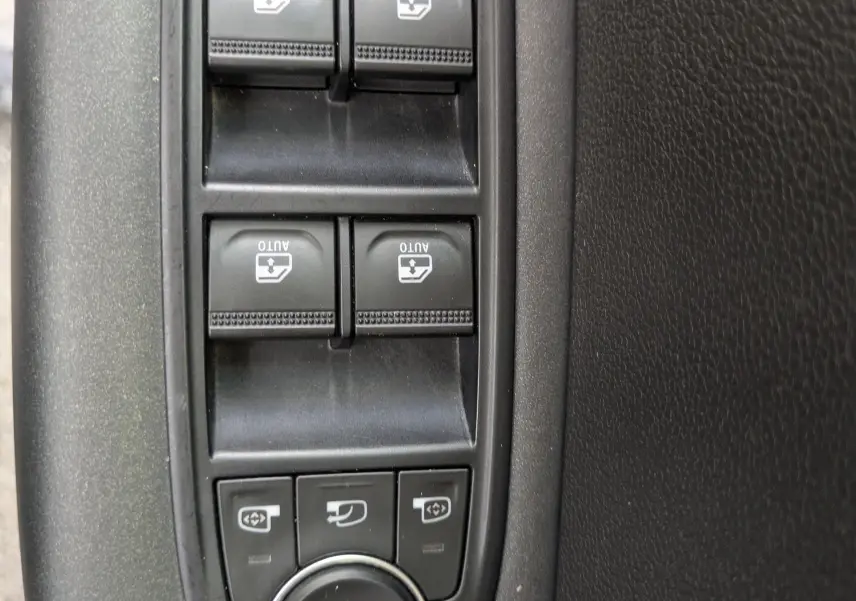 Vue rapprochée des commandes de lève-vitres et réglages des rétroviseurs côté conducteur d’un Renault Captur noir 2020.