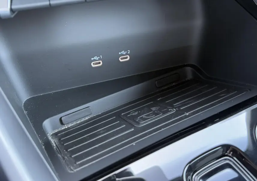 Vue rapprochée de la console centrale noire de l'Audi A3 Sportback 2024 montrant deux ports USB-C et un espace de recharge sans fil.