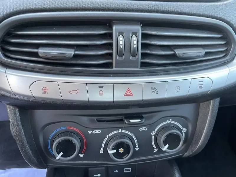 Vue rapprochée du tableau de bord de la Fiat Tipo 1.4 Street 2019, montrant les commandes de climatisation et les aérateurs noirs.