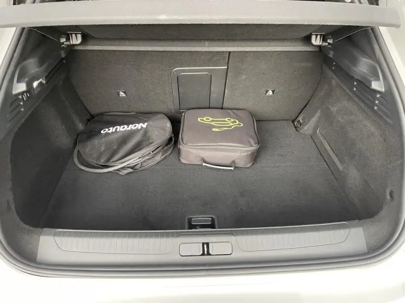 Vue plongeante sur le coffre spacieux et propre du DS4 gris 2023 Hybride E-Tense, avec deux sacs de rangement noirs.