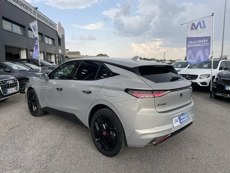 Vue 3/4 arrière droite d'une DS4 gris métallisé hybride rechargeable 2023 avec jantes noires et feux arrière LED distinctifs.