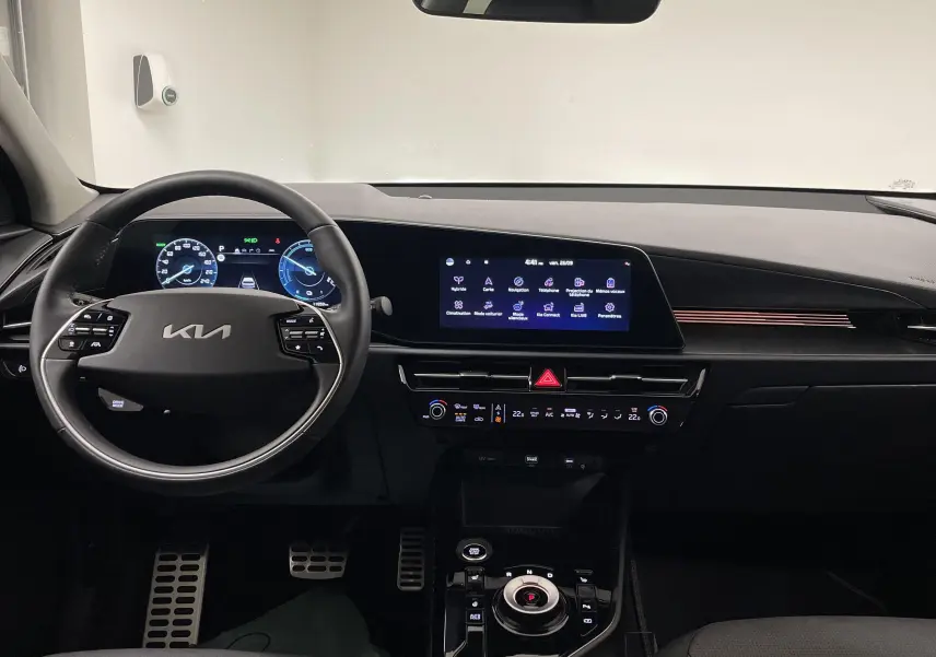 Vue intérieure du tableau de bord du Kia Niro 2025 blanc, avec écran tactile et volant multifonction.