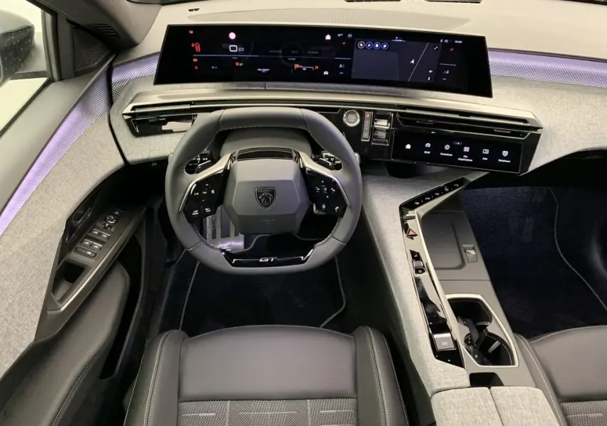 Vue intérieure frontale du Peugeot 3008 Hybrid GT 2025, tableau de bord numérique panoramique et volant compact cuir noir GT.