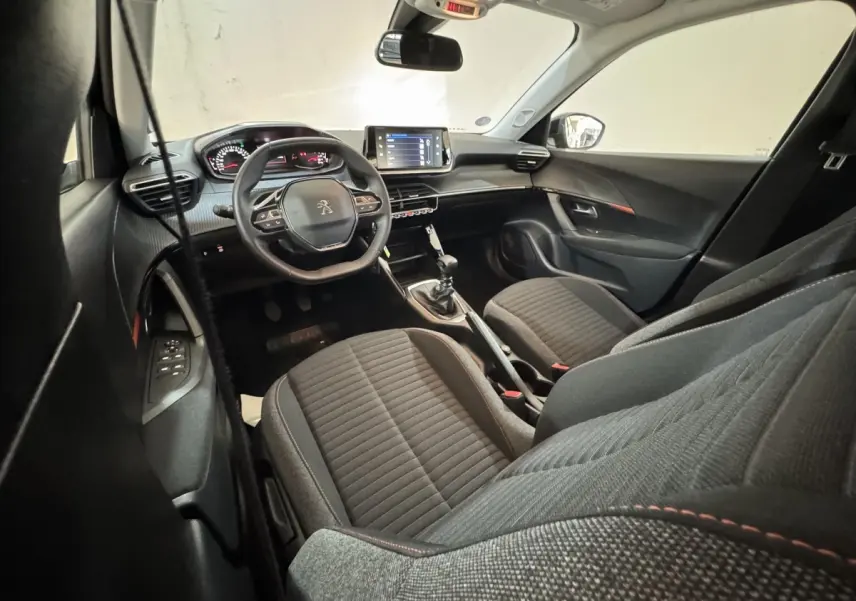 Intérieur avant du Peugeot 2008 noir, vue côté conducteur montrant tableau de bord, volant cuir et console centrale avec boîte manuelle.