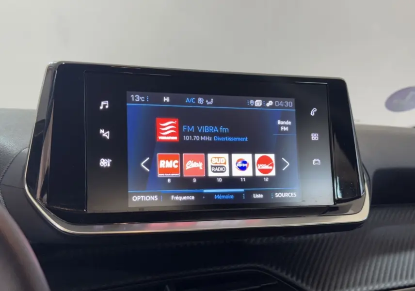 Écran tactile central de la Peugeot 2008 PureTech 130 noir affichant les stations radio FM en intérieur.