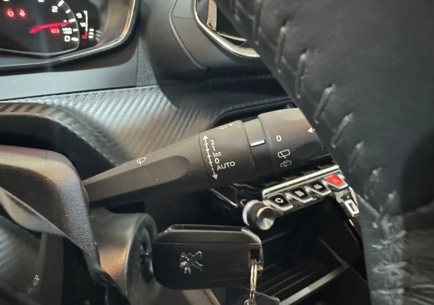 Gros plan sur le volant cuir noir et la commande d’essuie-glace du tableau de bord du Peugeot 2008 noir 2022.