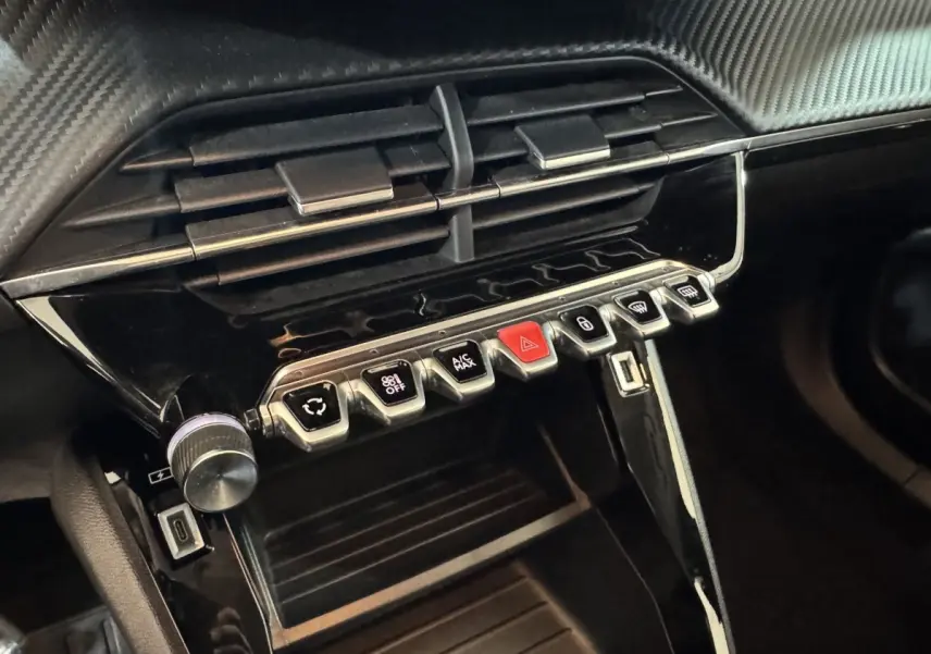 Gros plan sur la console centrale noire du Peugeot 2008 avec boutons de commande et prise USB visible.