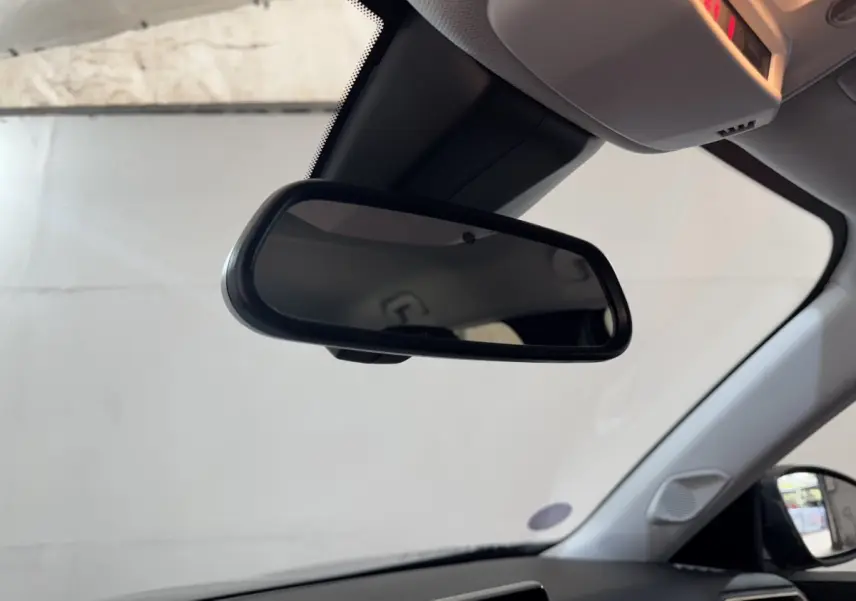 Vue intérieure du rétroviseur central d’une Peugeot 2008 noire, avec partie du tableau de bord et vitre latérale visibles.