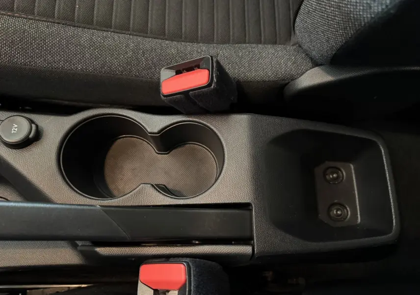 Vue rapprochée de la console centrale noire avec porte-gobelets et frein à main, sièges tissu gris foncé Peugeot 2008.