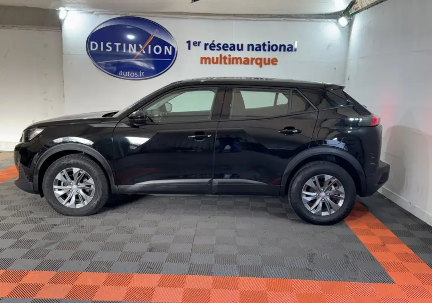 Profil côté gauche d'un Peugeot 2008 noir 2022 garé en intérieur, avec jantes alliage et rétroviseurs ton caisse.