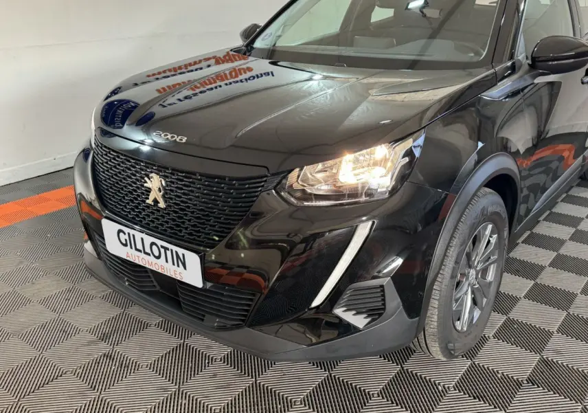 Vue 3/4 avant droit d'un Peugeot 2008 noir avec calandre noire et phares allumés dans un showroom.