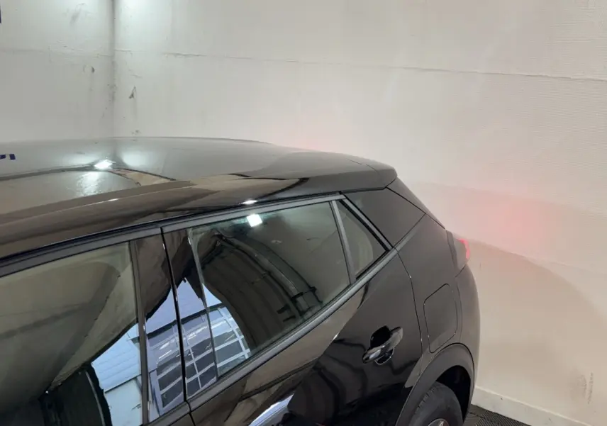 Vue arrière côté droit d’un Peugeot 2008 noir brillant, mettant en valeur la ligne de toit et la porte arrière.