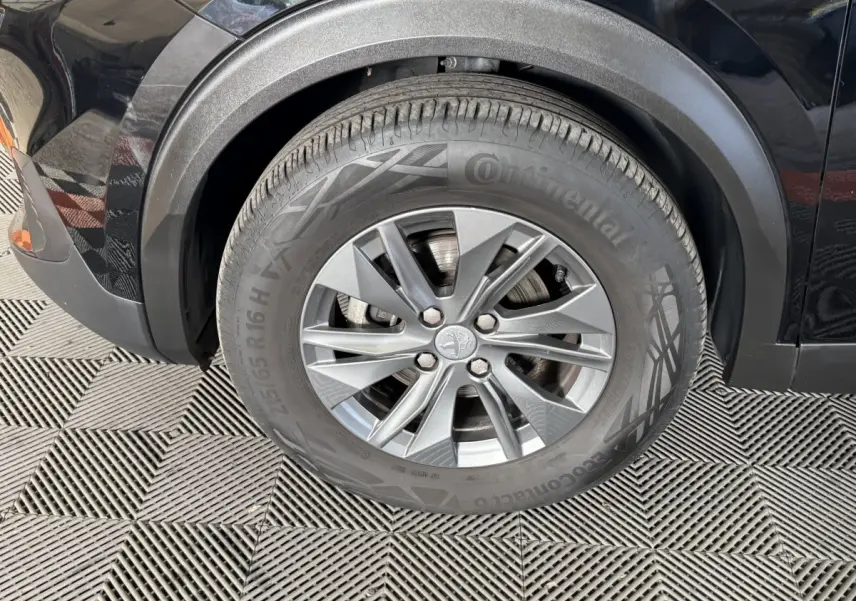 Gros plan sur la roue avant gauche d’un Peugeot 2008 noir, avec passage de roue en plastique noir mat.