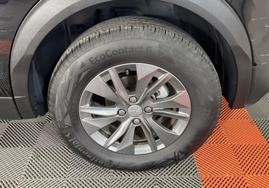 Gros plan sur la roue avant droite d’un Peugeot 2008 noir, mettant en valeur la jante alliage et le pneu Continental EcoContact 6.