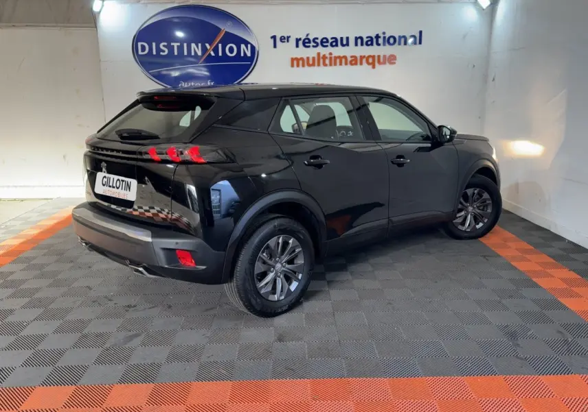 Vue 3/4 arrière droite d'un Peugeot 2008 noir 2022 dans un showroom avec sol gris et orange.