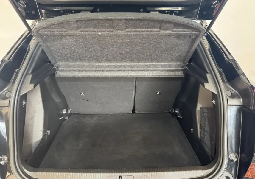 Coffre ouvert vu de l'arrière d'une Peugeot 2008 noire, montrant un espace de chargement propre et spacieux.