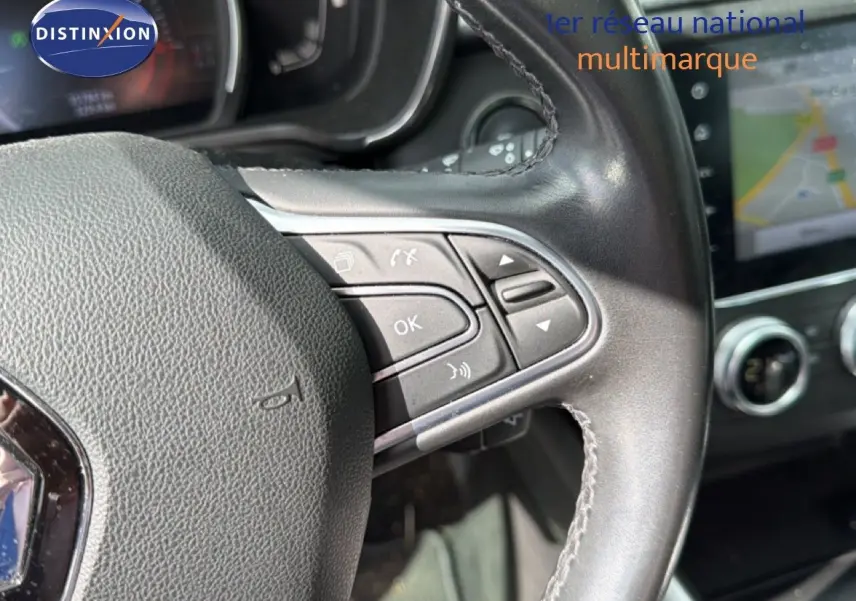 Gros plan sur le volant en cuir noir du Renault Kadjar 2019 avec commandes intégrées et écran tactile en arrière-plan.