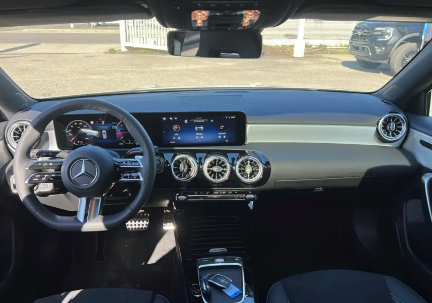 Vue intérieure avant de la Mercedes Classe A 200D Exclusive Design avec tableau de bord numérique et volant cuir multifonctions.
