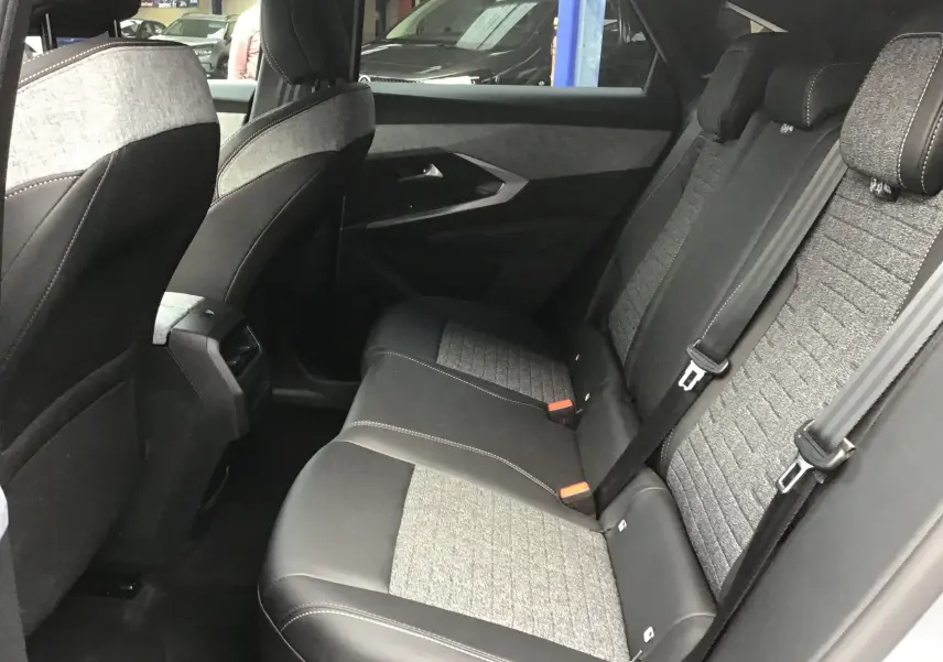 Vue intérieure côté droit des sièges arrière du Peugeot 3008 1.2 Hybrid 145 Allure avec sellerie tissu et cuir gris.