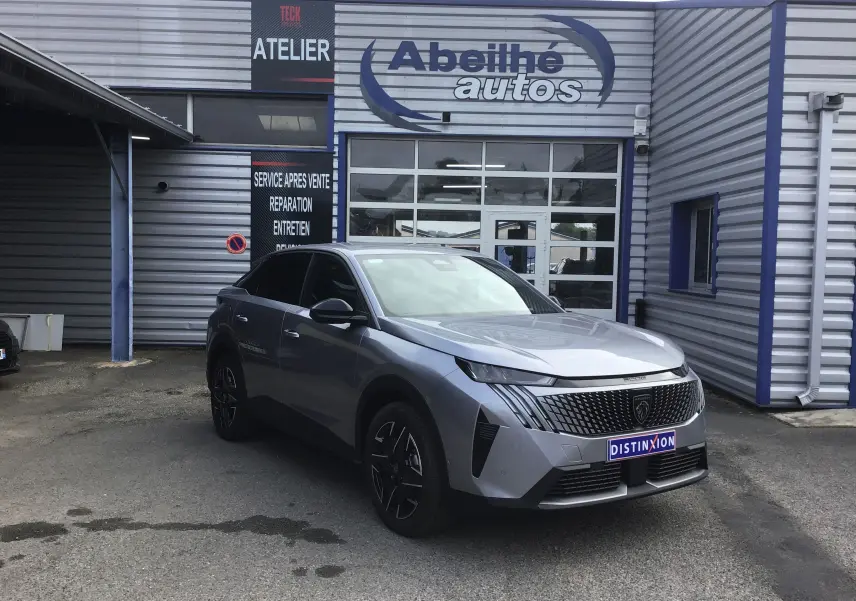 Peugeot 3008 1.2 Hybrid 145 en gris Artense, vue 3/4 avant droit devant un garage Abeilhé Autos.