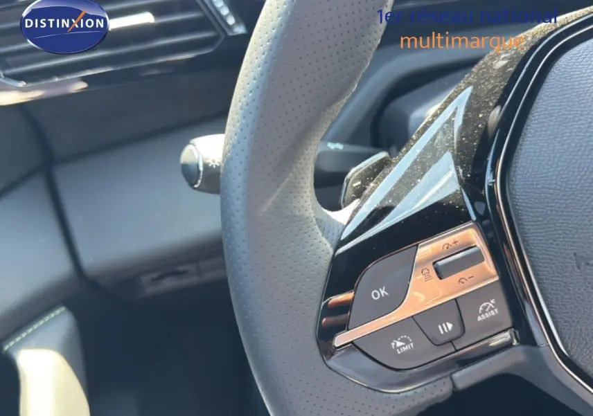 Gros plan sur le volant perforé gris avec commandes intégrées du Peugeot 308 Hybrid 145ch GT noir perle métal.