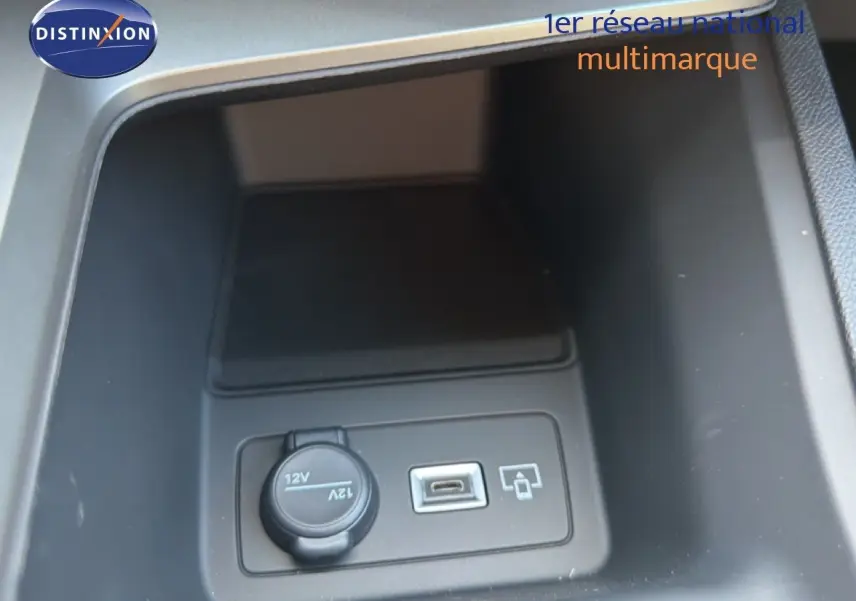 Gros plan sur la prise 12V et port USB dans le rangement central d'une Peugeot 308 Hybrid 145ch GT noir perle métal.