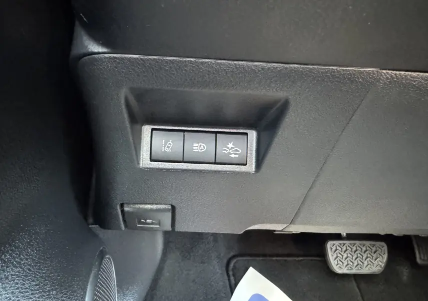 Gros plan sur les commandes de sécurité sous le tableau de bord d'une Toyota Yaris Hybride blanche, version GR Sport 2020.