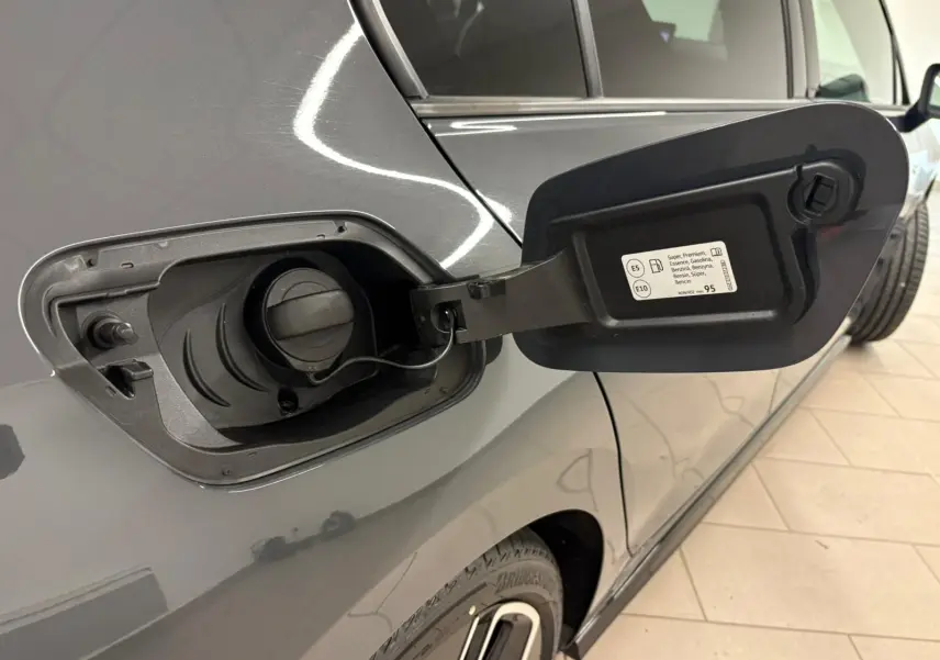 Gros plan sur la trappe à carburant ouverte côté gauche d'une Volkswagen Golf gris dauphin 2025.