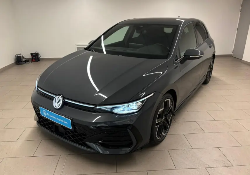 Volkswagen Golf 1.5 eTSI R-Line Gris Dauphin vue 3/4 avant droit en intérieur avec phares allumés.