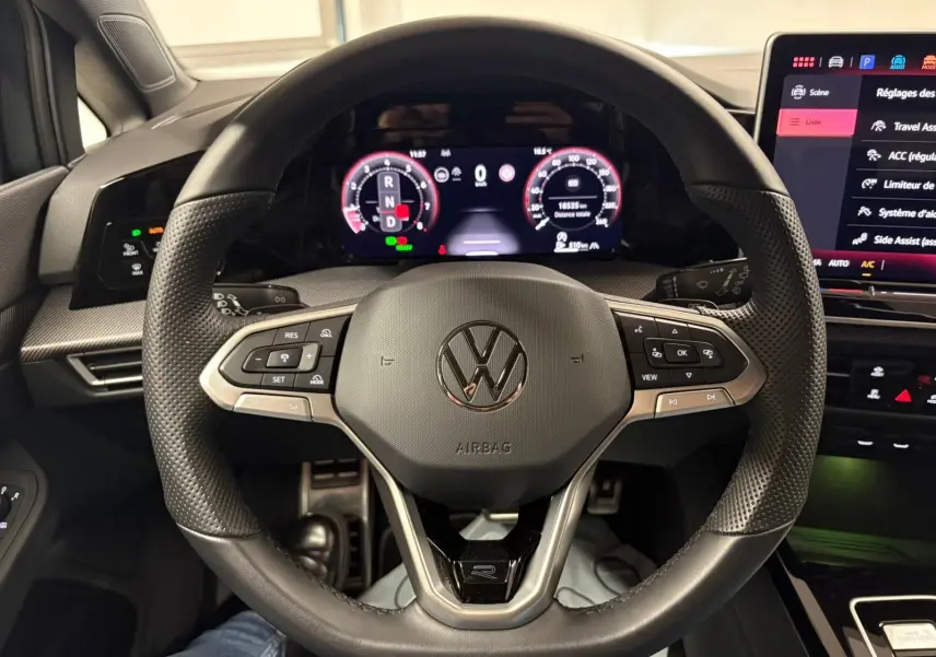 Vue rapprochée du volant multifonction noir de la Volkswagen Golf 1.5 eTSI 150 DSG7 R-Line Edition avec tableau de bord numérique.