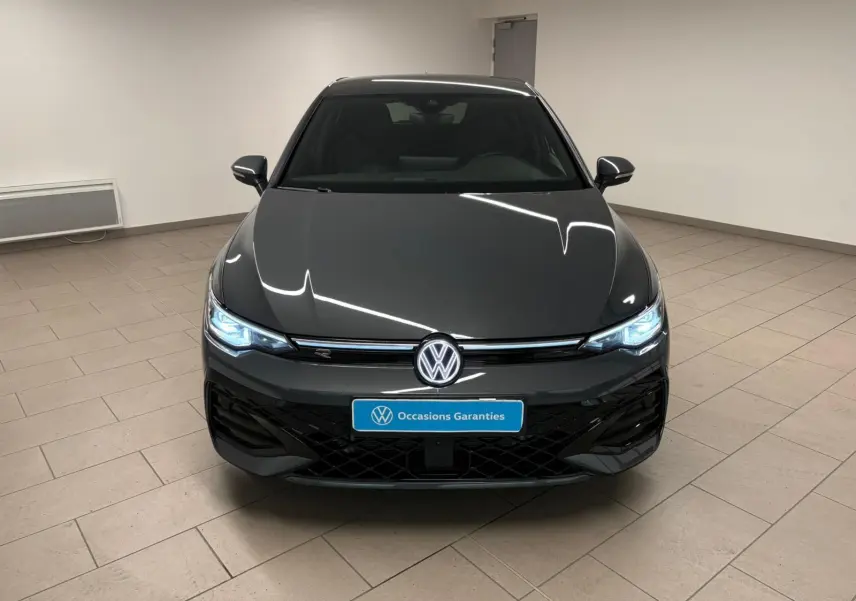 Vue frontale d'une Volkswagen Golf 1.5 eTSI 150 DSG7 R-Line Edition en gris dauphin avec phares LED allumés en intérieur.