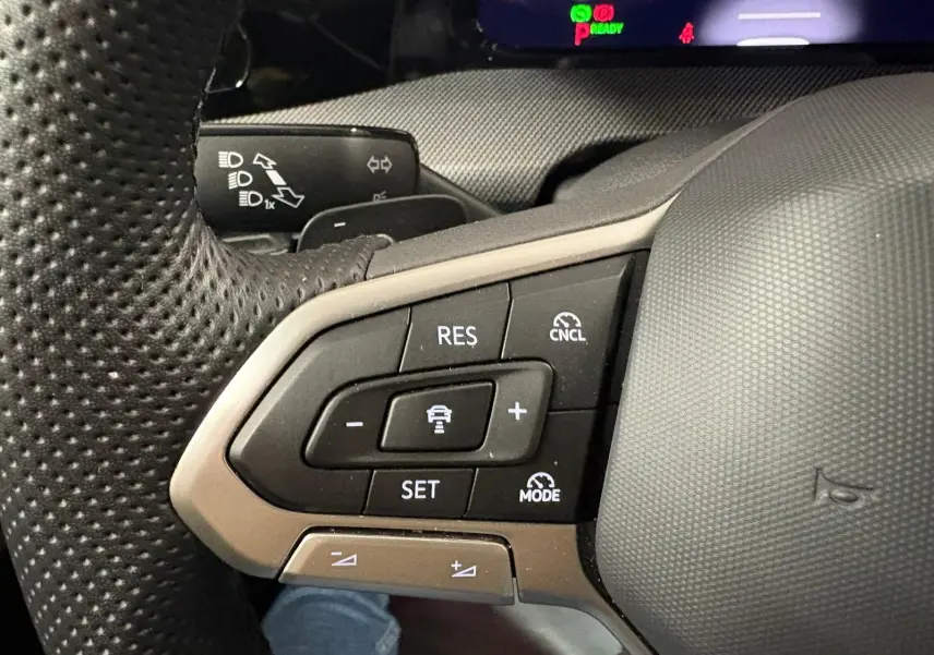 Gros plan sur les commandes de régulateur de vitesse au volant d’une Volkswagen Golf 1.5 eTSI gris Dauphin, 2025.