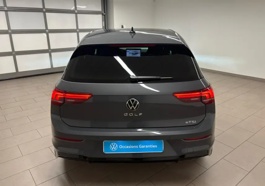 Vue arrière d'une Volkswagen Golf 1.5 eTSI gris dauphin avec feux LED allumés dans un garage.
