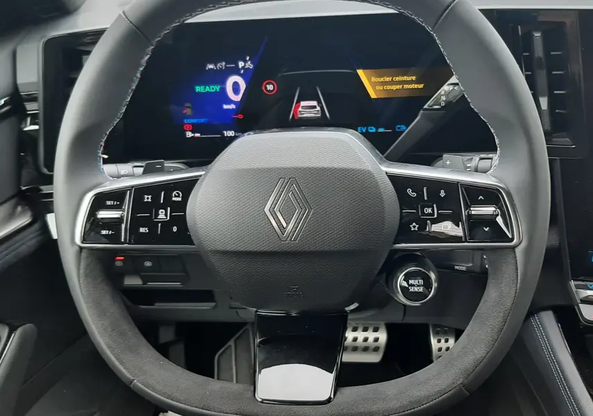Vue intérieure centrée sur le volant multifonction du Renault Austral hybride avec tableau de bord numérique lumineux.