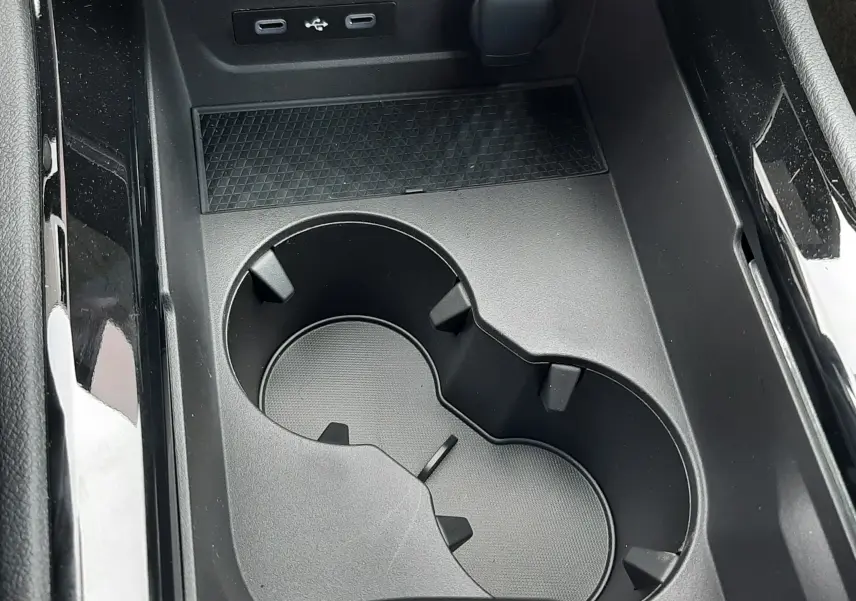Gros plan sur la console centrale noire du Renault Austral avec porte-gobelets et ports USB visibles.