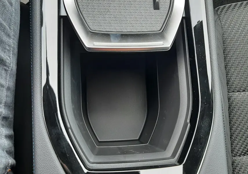 Vue rapprochée de la console centrale noire brillante avec zone de recharge sans fil du Renault Austral blanc nacré intérieur noir.