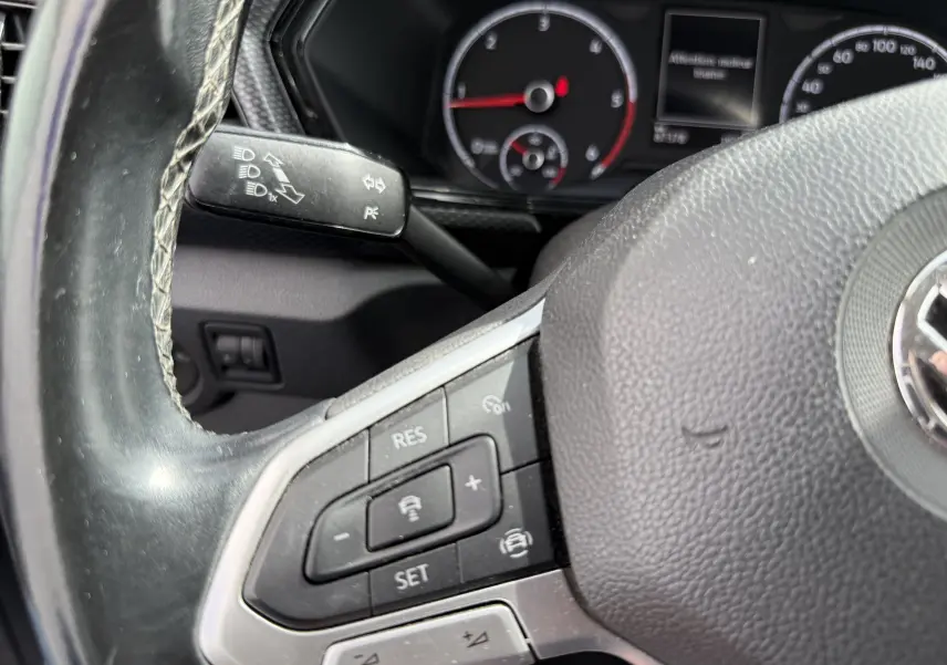 Gros plan sur le volant cuir noir et les commandes multifonctions côté gauche du Volkswagen T-Cross gris de 2019.